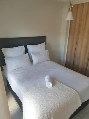 a white bed with a rolled up towel on it at 3 Bedroom Apartment The Blyde Crystal Lagoon in Pretoria