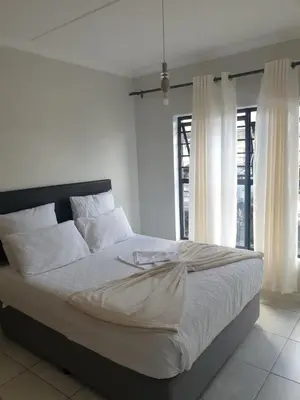 a bed with white sheets and pillows in a bedroom at 3 Bedroom Apartment The Blyde Crystal Lagoon in Pretoria