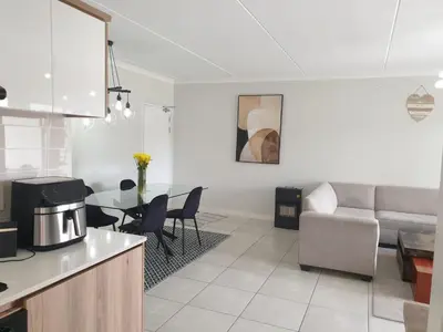 a kitchen and living room with a table and a couch at 3 Bedroom Apartment The Blyde Crystal Lagoon in Pretoria