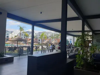 a restaurant with people sitting at tables and umbrellas at 3 Bedroom Apartment The Blyde Crystal Lagoon in Pretoria