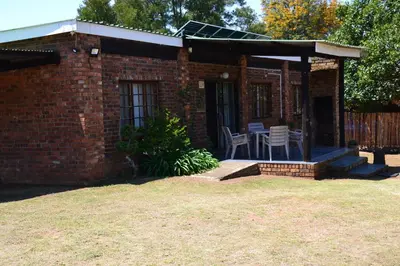 a brick house with a patio with a table and chairs at Trout Ways in Waterval Boven