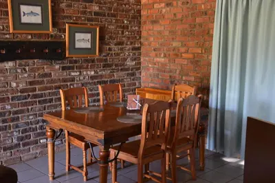 a wooden table and chairs in front of a brick wall at Trout Ways in Waterval Boven