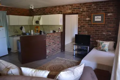 a room with a kitchen and a living room with a couch at Trout Ways in Waterval Boven