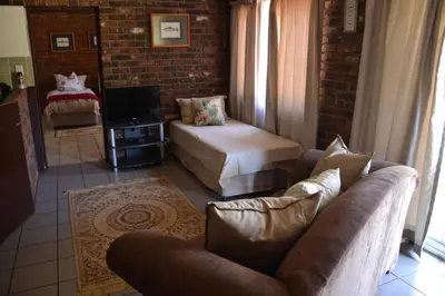 a living room with a couch and a bed at Trout Ways in Waterval Boven