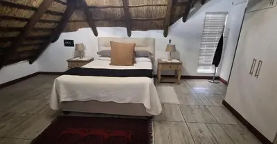 a bedroom with a bed and two tables with lamps at Green Haven Guest Lodge in Pretoria