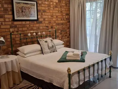 a bed in a bedroom with a brick wall at Green Haven Guest Lodge in Pretoria