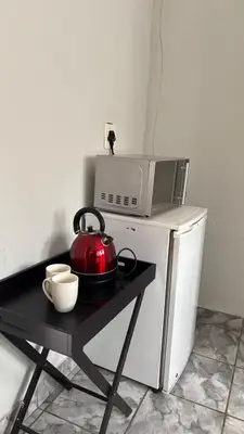 a tea kettle on a table next to a microwave at The N1 Farm Place in Pretoria