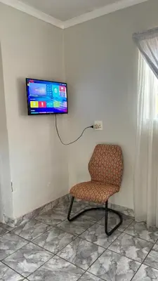 a room with a chair and a television on a wall at The N1 Farm Place in Pretoria