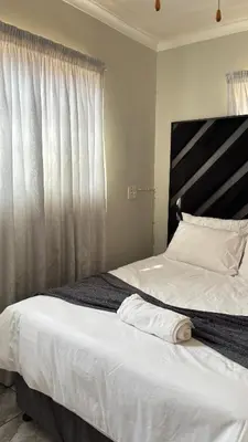 a bedroom with a large bed with a large window at The N1 Farm Place in Pretoria