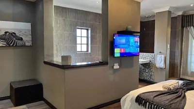 a bedroom with a bed and a television on a wall at The N1 Farm Place in Pretoria