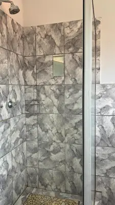 a shower with a glass door in a bathroom at The N1 Farm Place in Pretoria
