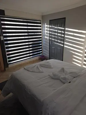 a white bed in a room with two large windows at The Good Samaritan 4 in Witbank