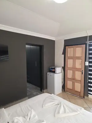 a bedroom with a bed and a door and a refrigerator at The Good Samaritan 4 in Witbank