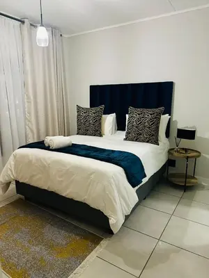 a bedroom with a large bed with a blue headboard at Kaso holidays in Pretoria