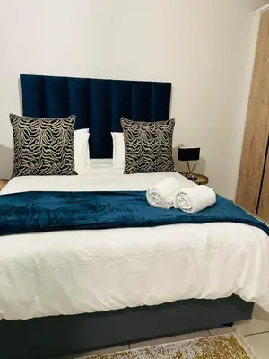 a large bed with blue and white sheets and pillows at Kaso holidays in Pretoria