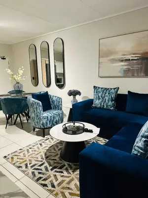 a living room with a blue couch and chairs at Kaso holidays in Pretoria