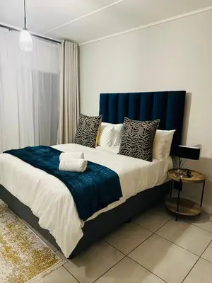 a bedroom with a large bed with a blue headboard at Kaso holidays in Pretoria