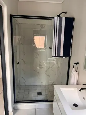 a bathroom with a shower and a white sink at Kaso holidays in Pretoria
