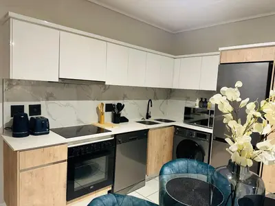 a kitchen with white cabinets and a table at Kaso holidays in Pretoria