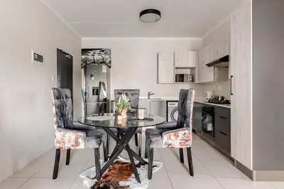 a dining room with a glass table and chairs at Spacious Executive Luxury Apartment in Midrand
