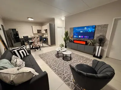 a living room with a couch and chairs and a tv at Spacious Executive Luxury Apartment in Midrand