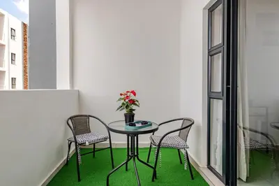 a small table with chairs and a vase of flowers on a balcony at Spacious Executive Luxury Apartment in Midrand