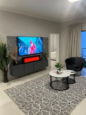 a living room with a flat screen tv and a table at Spacious Executive Luxury Apartment in Midrand