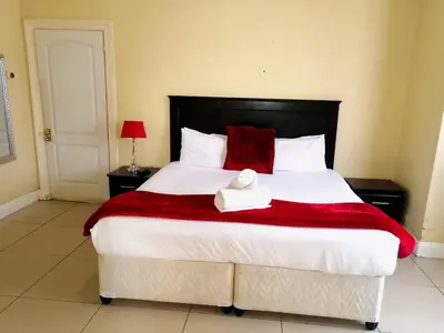 a bedroom with a large bed with a red blanket at 39 Maple in Pretoria