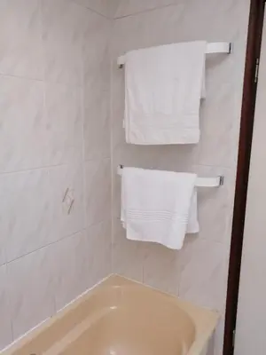 a bathroom with white towels and a bath tub at 39 Maple in Pretoria