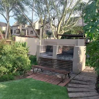 a bench in a yard with a fence and grass at Travellor's relaxation unit, secure 1,5 bedrooms in Sandton