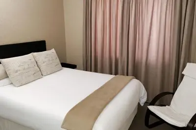 a bedroom with a white bed and a chair at Lafenis in Pretoria