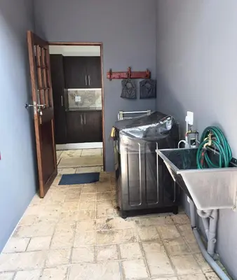 a laundry room with a sink and a trash can at Brett's Place in Warmbaths