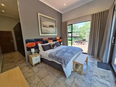 a bedroom with a large bed and a large window at Brett's Place in Warmbaths