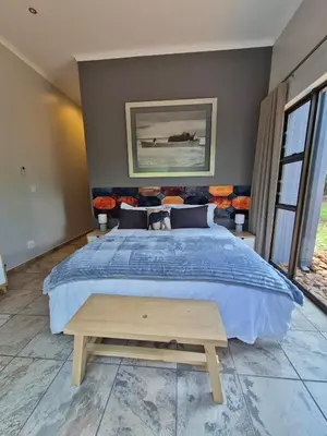a bedroom with a large bed with a blue comforter at Brett's Place in Warmbaths