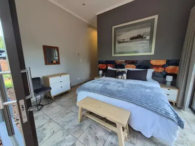 a bedroom with a large bed with a blue comforter at Brett's Place in Warmbaths