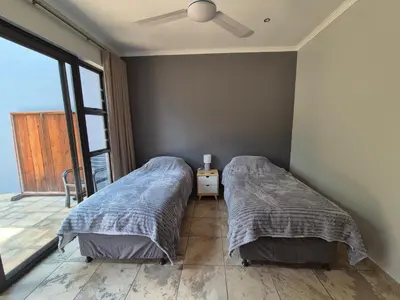 a bedroom with two beds and a balcony at Brett's Place in Warmbaths
