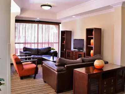 a living room with leather furniture and a television at Premier Hotel Pretoria in Pretoria