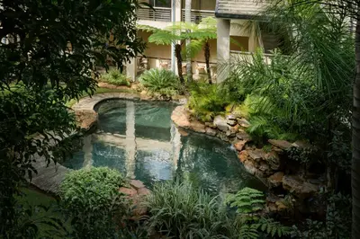 a swimming pool with a waterfall in a garden at Premier Hotel Pretoria in Pretoria