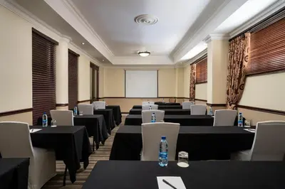 a conference room with tables and chairs and a screen at Premier Hotel Pretoria in Pretoria