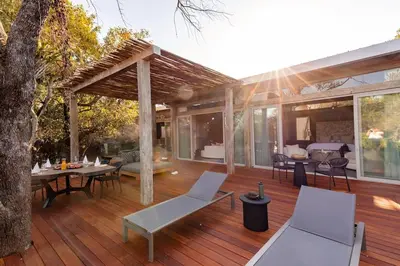 a wooden deck with a pergola and tables and chairs at Kapama Karula in Kapama Private Game Reserve
