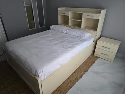 a bed with a white bed frame and a night stand at Sunrise Lodge in Phalaborwa