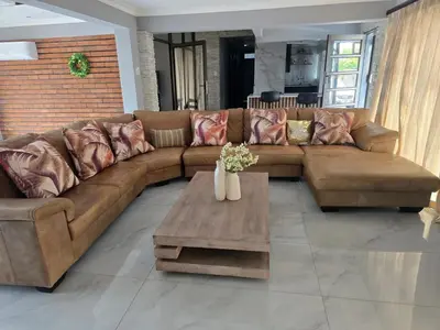 a living room with a brown couch and a coffee table at Sunrise Lodge in Phalaborwa