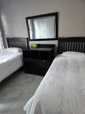 a bedroom with two beds and a dresser with a mirror at Sunrise Lodge in Phalaborwa