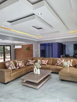 a living room with a brown couch and a table at Sunrise Lodge in Phalaborwa