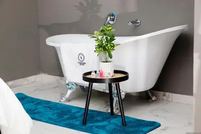 a bathroom with a white tub and a plant on a table at Siyamthanda Boutique in Louis Trichardt