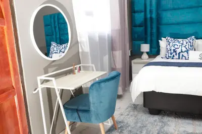 a bedroom with a bed and a mirror and a blue chair at Siyamthanda Boutique in Louis Trichardt