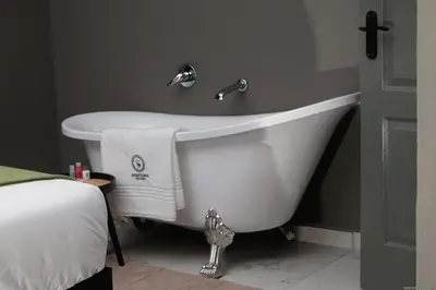 a white bath tub in a bathroom with a bed at Siyamthanda Boutique in Louis Trichardt