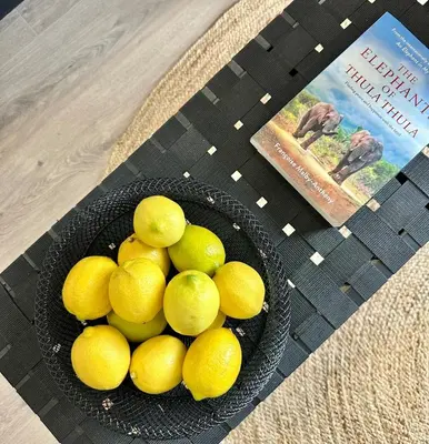 a bowl of lemons on a table next to a book at Explore Ellipse - The Sage Apartment in Midrand