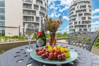 a table with a plate of fruit and a bottle of wine at Ellipse Soleya in Midrand