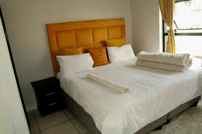 a bedroom with a bed with white sheets and a mirror at The Blyde Crystal Lagoons in Pretoria